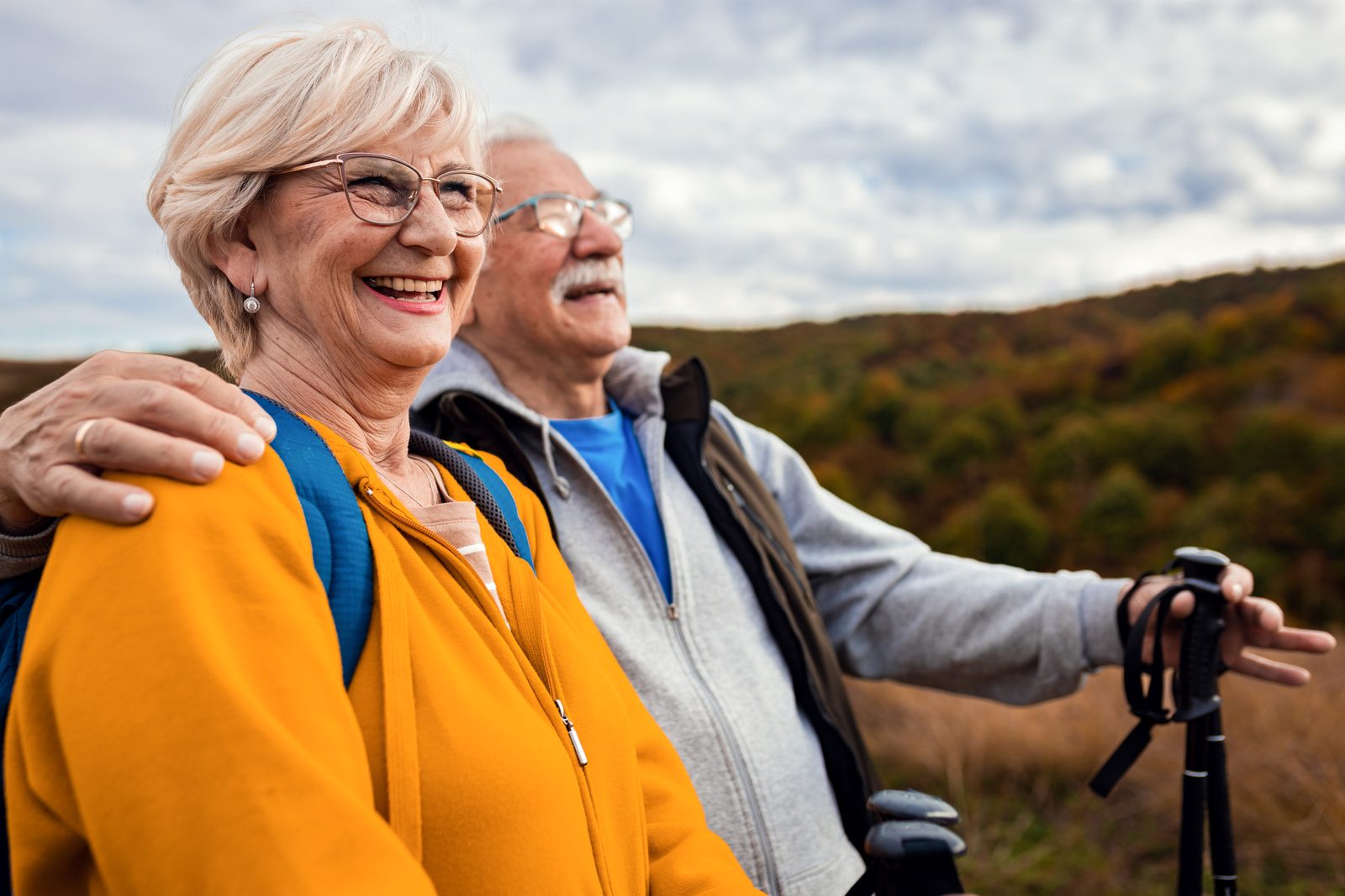 An older couple holding hands on a park bench, laughing together.