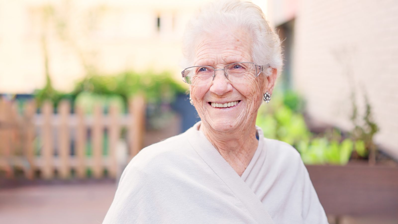 An older woman smiling outdoors in the daytime.